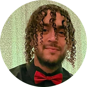 A man with curly hair and a beard, wearing a black shirt and a red bow tie.