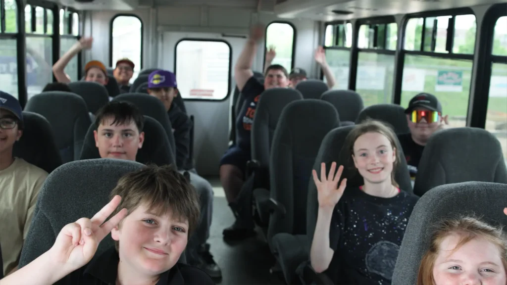 Inside of the BGCCB bus with happy children waving at the camera.